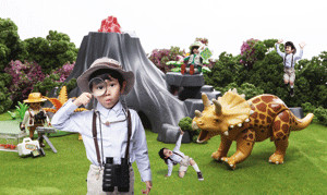 공룡이 있는 동물원을 배경으로 서있는 남자아이