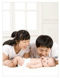 누워있는 신생아를 보는 여성과 남성